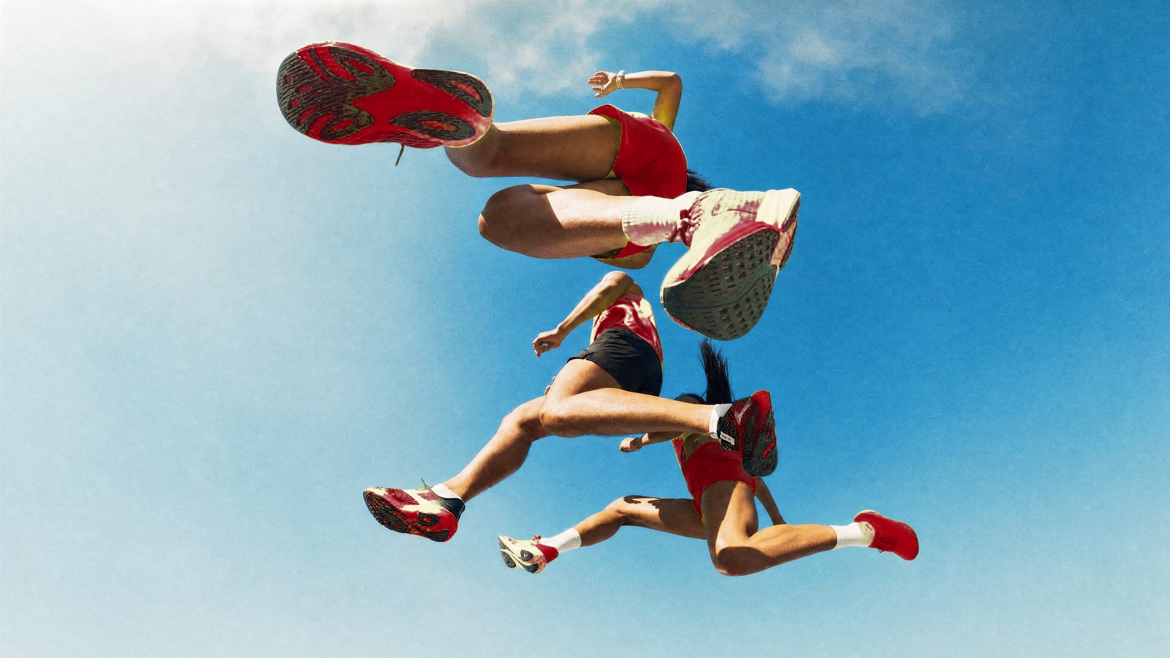 Runners leaping against a blue sky